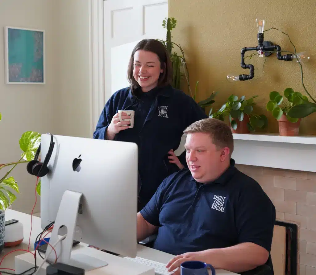 Ryan and Katie, members's of shout loud social's team standing at ryan's desk